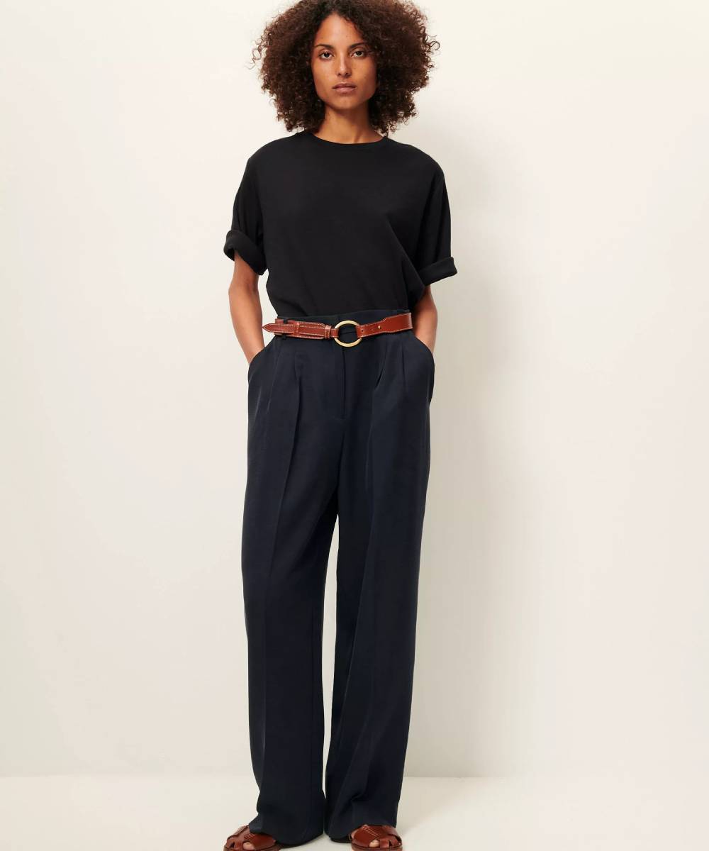 Foto de cuerpo entero de una modelo posando con Imagen de modelo llevando una camiseta negra, acanalada, con mangas holgadas y con dobladillo. Tiene las manos en los bolsillos del pantalón. La Folie Santander.